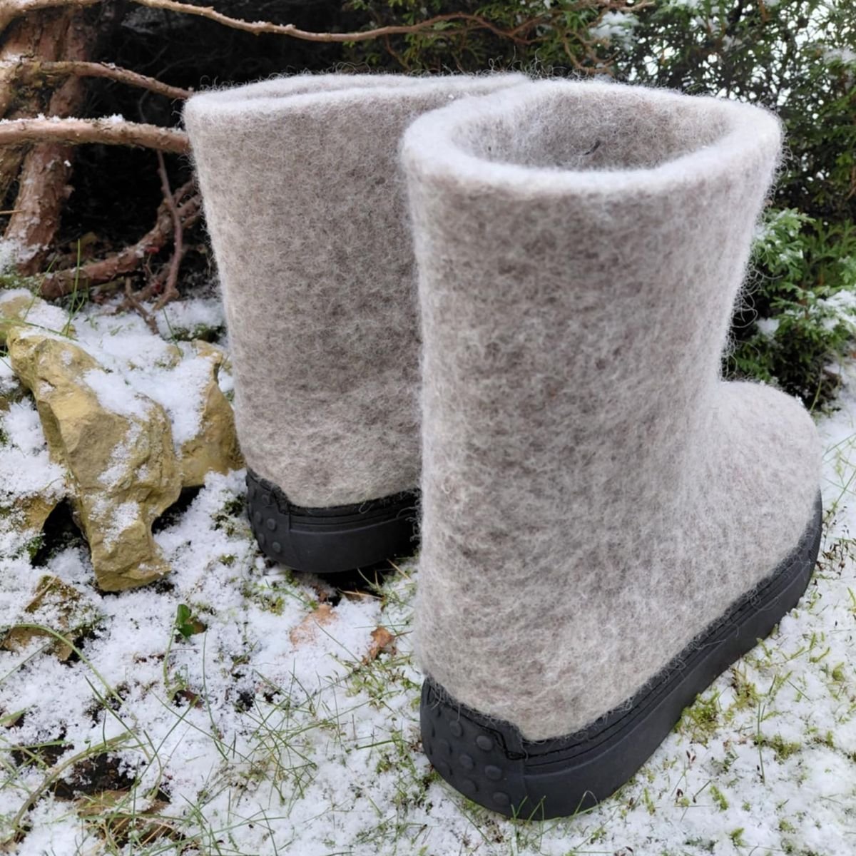 Šviesūs veltiniai batai su guminiais padais, vaizdas iš galo, stovintys ant sniego